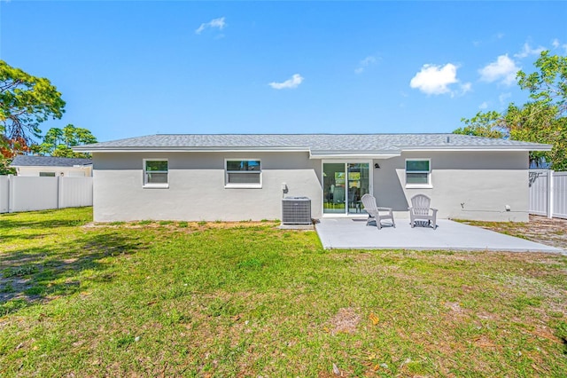 rear view of property featuring a patio, central AC unit, fence, a yard, and stucco siding