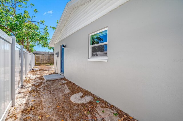 view of side of home with a fenced backyard and stucco siding