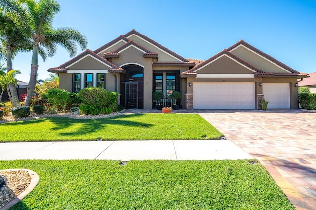 mediterranean / spanish home with stucco siding, driveway, an attached garage, and a front lawn