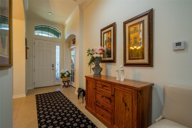 entryway featuring light tile patterned floors, baseboards, arched walkways, and ornamental molding