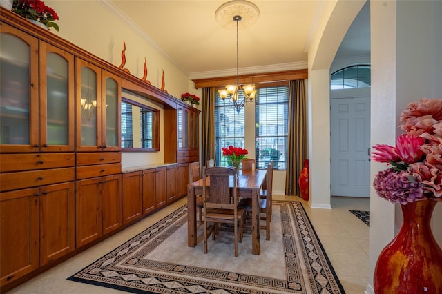 dining space featuring ornamental molding, arched walkways, an inviting chandelier, light tile patterned floors, and baseboards