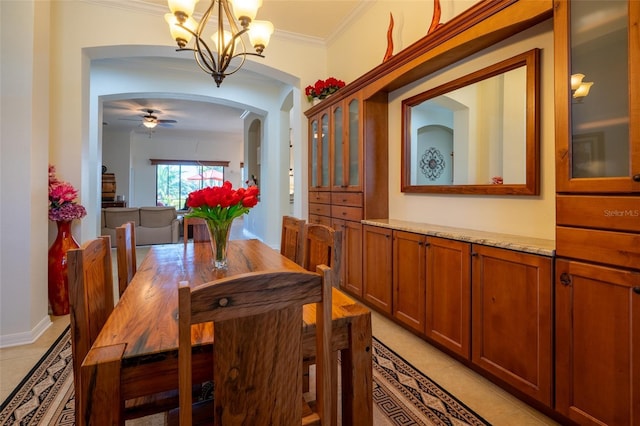 dining room with light tile patterned floors, arched walkways, crown molding, and ceiling fan with notable chandelier