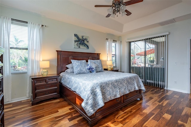 bedroom featuring a tray ceiling, visible vents, wood finished floors, and access to outside