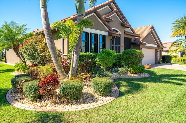 view of front of property featuring a front lawn, concrete driveway, a garage, and stucco siding