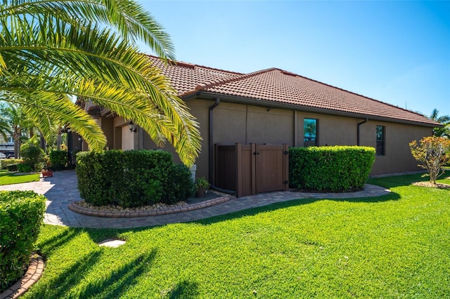 view of home's exterior with stucco siding, a lawn, and a tiled roof