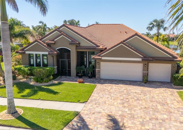 mediterranean / spanish home featuring stucco siding, driveway, an attached garage, and a tiled roof