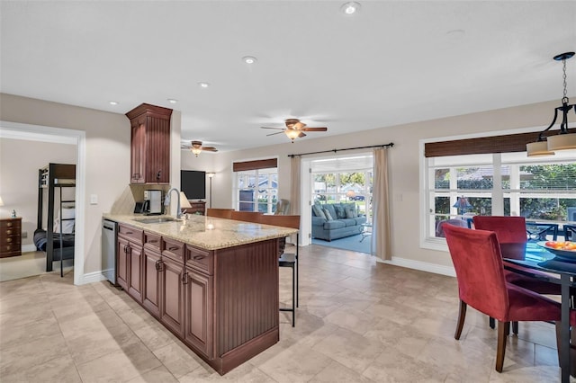 kitchen with a sink, ceiling fan, a breakfast bar, a peninsula, and stainless steel dishwasher