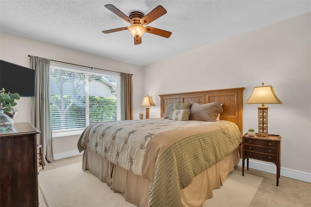 bedroom featuring light colored carpet, a textured ceiling, baseboards, and a ceiling fan