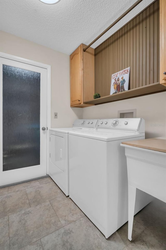 laundry room with cabinet space, a textured ceiling, and independent washer and dryer