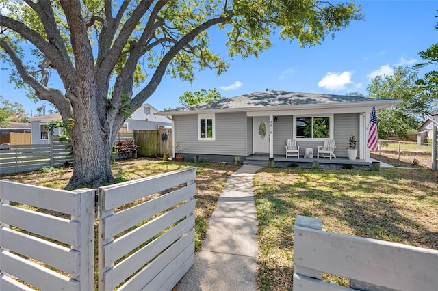 bungalow featuring a fenced front yard, a porch, and a front lawn