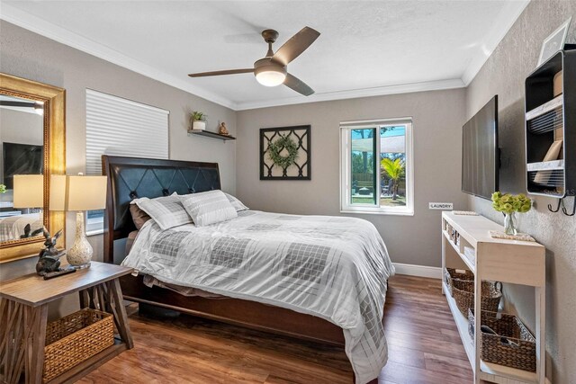 bedroom featuring a ceiling fan, crown molding, wood finished floors, and baseboards