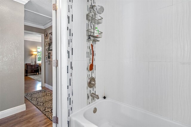 full bathroom featuring ornamental molding, a textured ceiling, wood finished floors, tub / shower combination, and baseboards