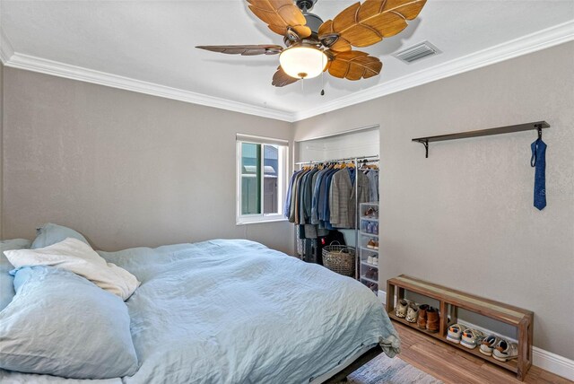 bedroom with visible vents, crown molding, and wood finished floors