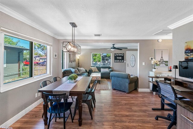 dining room with visible vents, crown molding, baseboards, wood finished floors, and a textured ceiling