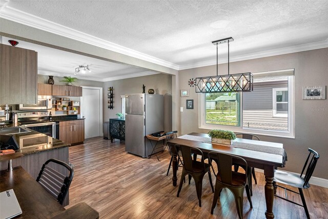 dining space featuring light wood finished floors, a textured ceiling, baseboards, and ornamental molding