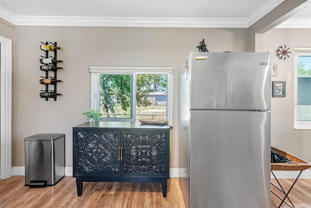 kitchen with ornamental molding, freestanding refrigerator, and wood finished floors