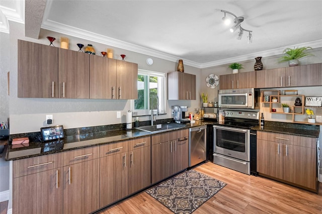 kitchen with appliances with stainless steel finishes, light wood-type flooring, crown molding, and a sink