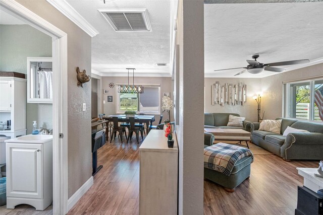 living room featuring visible vents, plenty of natural light, a textured ceiling, and wood finished floors