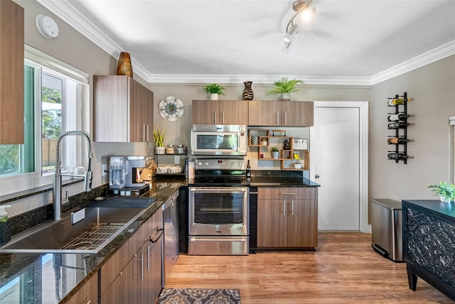 kitchen featuring light wood-style flooring, stainless steel appliances, crown molding, and a sink