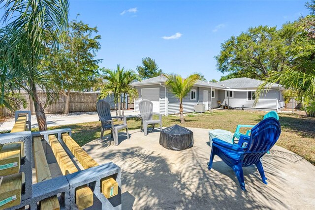 exterior space featuring a fire pit, fence, central air condition unit, a patio area, and an attached garage