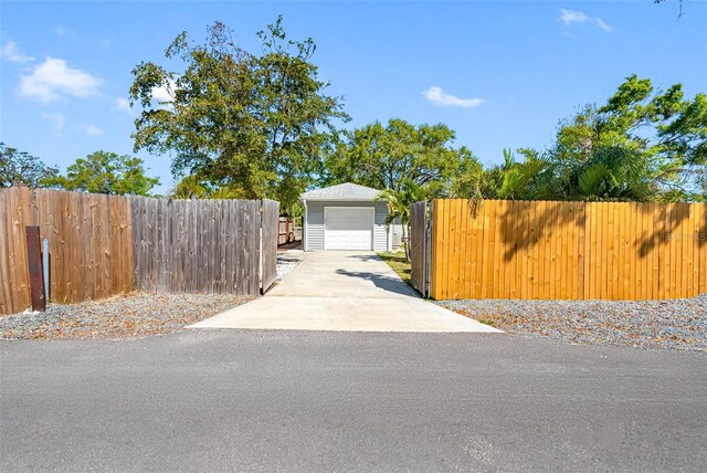 view of front of house featuring a detached garage, an outdoor structure, driveway, and fence