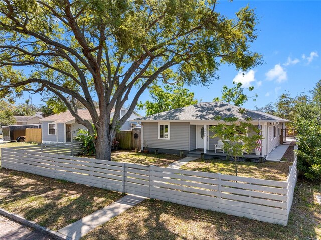 ranch-style home featuring a fenced front yard and a porch