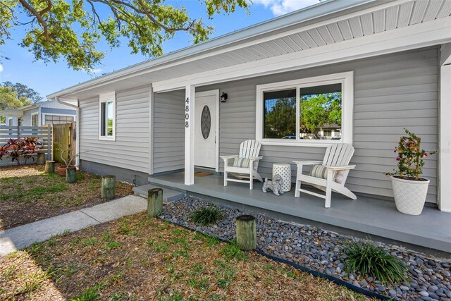 entrance to property featuring fence and covered porch