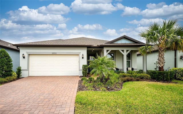 view of front of house with decorative driveway, a front lawn, an attached garage, and stucco siding