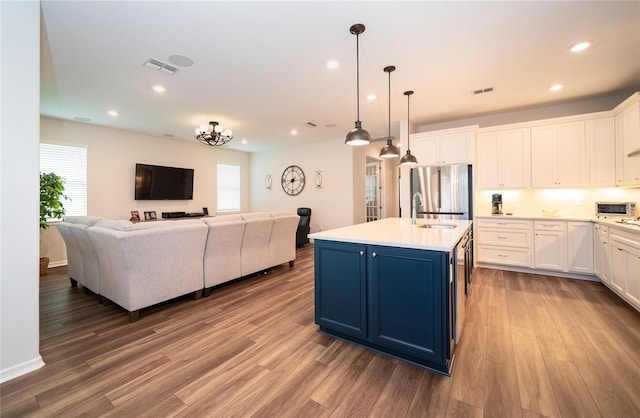 kitchen with a sink, blue cabinets, open floor plan, and stainless steel refrigerator