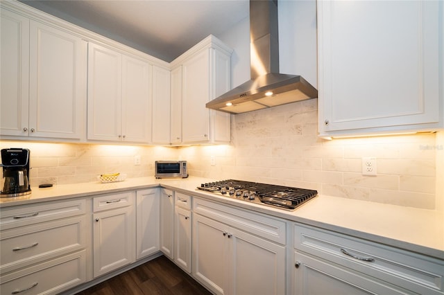 kitchen featuring decorative backsplash, light countertops, wall chimney exhaust hood, and stainless steel gas stovetop