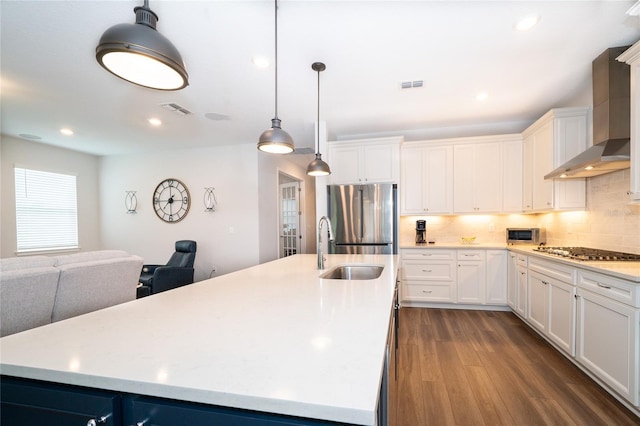 kitchen featuring a sink, wall chimney range hood, visible vents, and stainless steel appliances