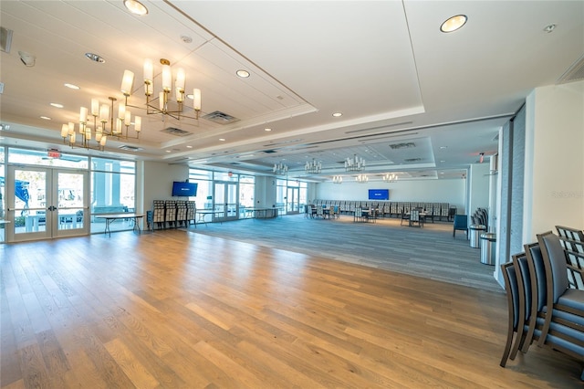 exercise room featuring visible vents, a healthy amount of sunlight, french doors, and a raised ceiling