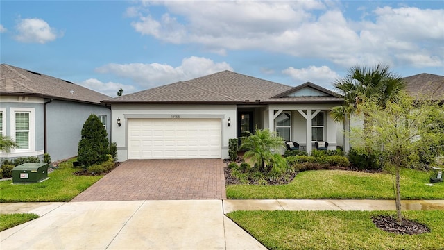 view of front of property featuring a front lawn, decorative driveway, an attached garage, and stucco siding