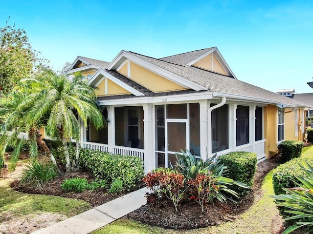 view of home's exterior with a shingled roof, a sunroom, and stucco siding