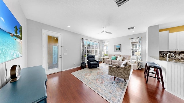 living area featuring dark wood-style floors, baseboards, visible vents, and recessed lighting