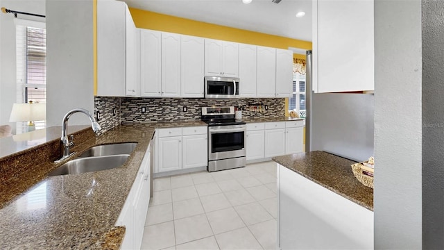 kitchen with backsplash, dark stone countertops, stainless steel appliances, and a sink