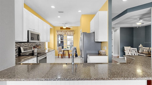 kitchen featuring arched walkways, stainless steel appliances, tasteful backsplash, visible vents, and white cabinets