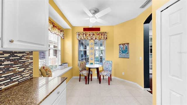 dining space with arched walkways, visible vents, baseboards, and light tile patterned floors