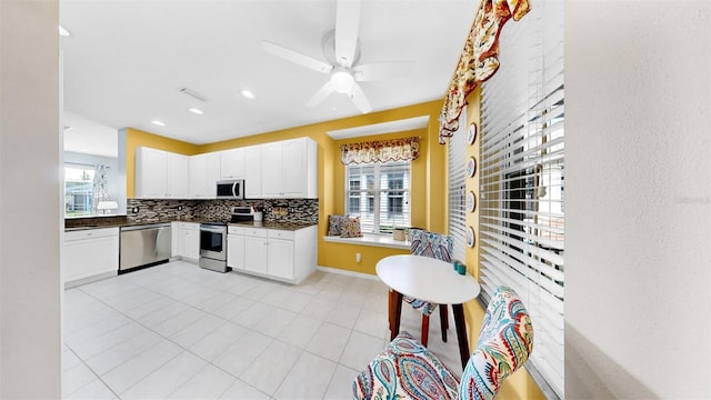 kitchen with tasteful backsplash, dark countertops, appliances with stainless steel finishes, a ceiling fan, and white cabinetry