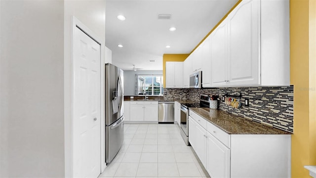 kitchen featuring tasteful backsplash, visible vents, white cabinets, stainless steel appliances, and a sink