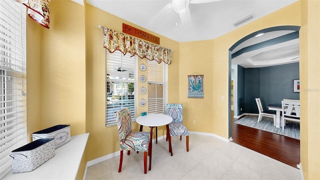 tiled dining room with ceiling fan, visible vents, baseboards, and a raised ceiling