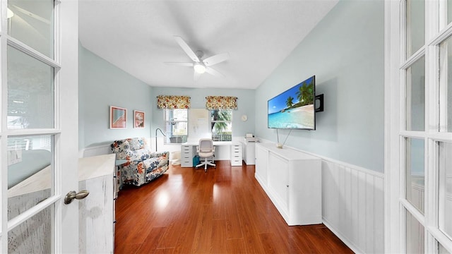 interior space with a wainscoted wall, a ceiling fan, and wood finished floors