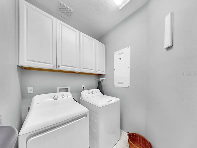 clothes washing area with cabinet space, visible vents, and washer and dryer