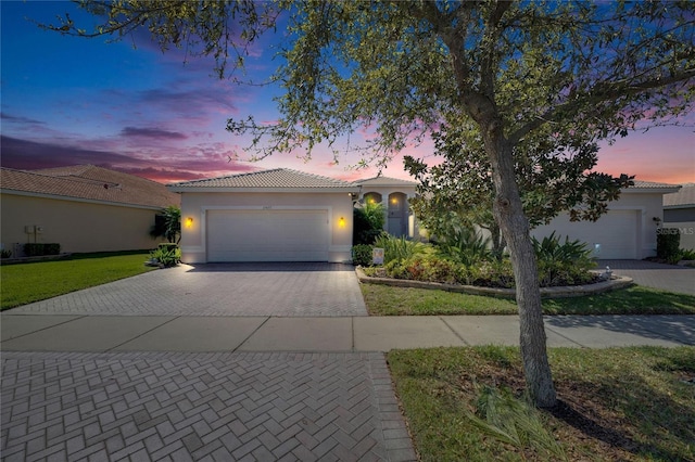 view of front of home with a tiled roof, a garage, decorative driveway, and stucco siding