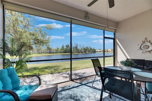 sunroom / solarium with a ceiling fan and a water view