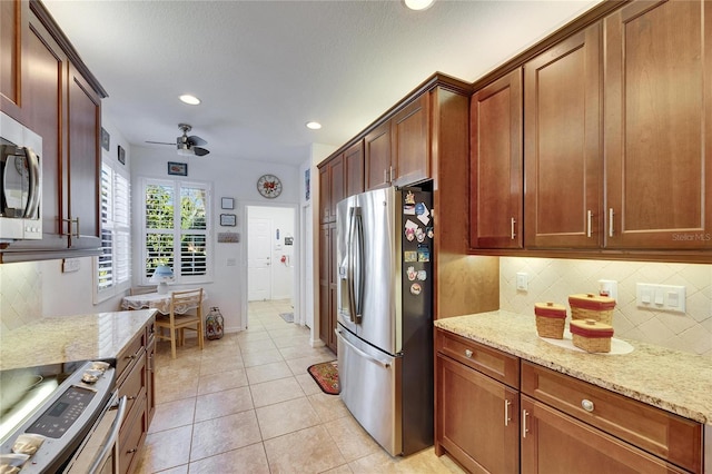 kitchen featuring a ceiling fan, light stone counters, tasteful backsplash, appliances with stainless steel finishes, and light tile patterned flooring