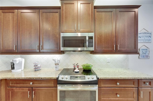 kitchen with backsplash, appliances with stainless steel finishes, and light stone countertops