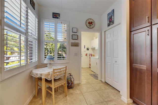 dining room featuring light tile patterned floors, baseboards, and washing machine and clothes dryer