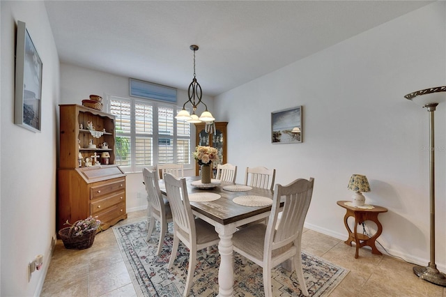 dining space featuring light tile patterned floors, baseboards, and a chandelier