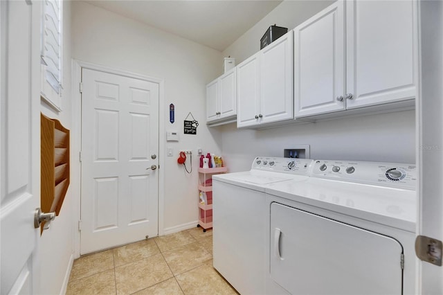 washroom with cabinet space, washer and dryer, baseboards, and light tile patterned flooring